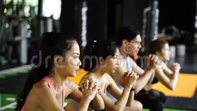 一群穿着<strong>运动</strong>服的亚洲年轻人在健身房里蹲着锻炼。 <strong>剧烈运动</strong>和健康